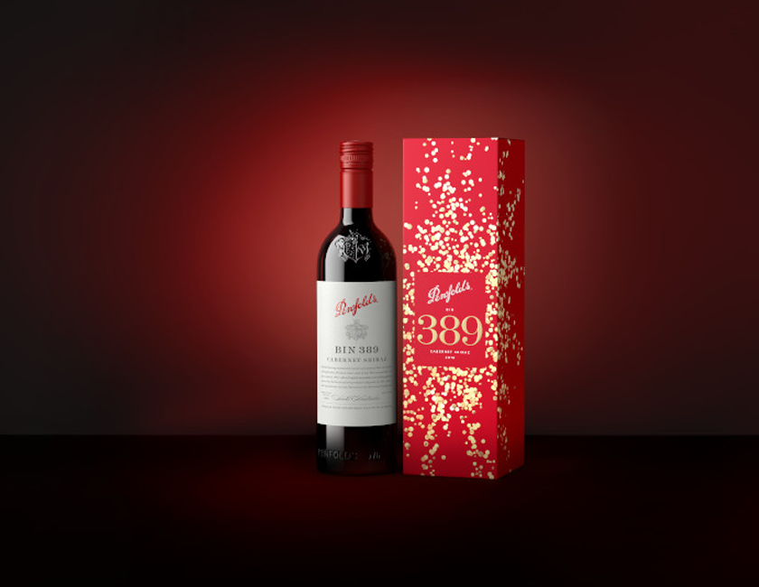 Bin 389 bottle next to red gift box covered in gold confetti