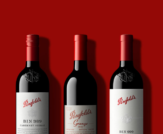 3 Penfolds wine bottles against red background